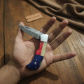 Handmade Damascus Folding Knife – Tricolor Resin Handle (Red, White & Blue) with Leather Sheath